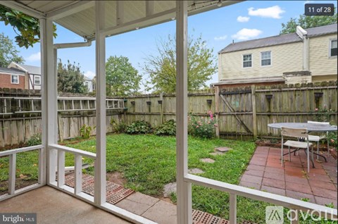 A patio with a table and chairs is framed by a white railing.