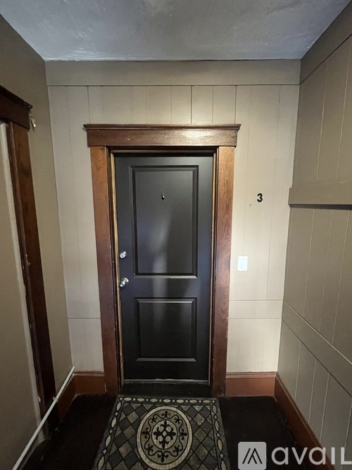 A black door with a wooden frame and a tiled floor with a pattern in the middle.