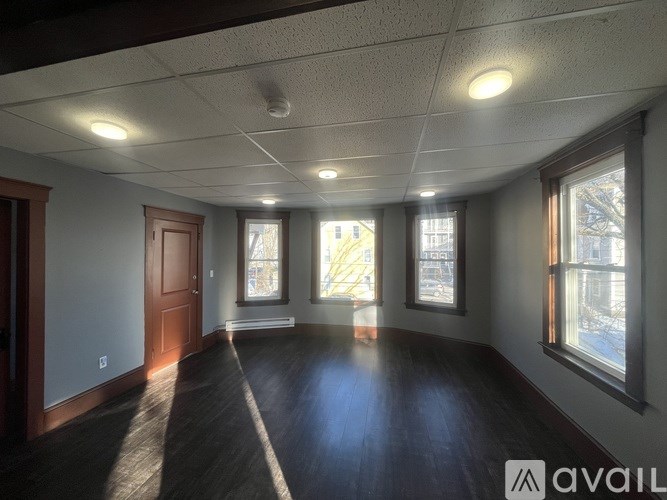 A spacious room with wooden floors and large windows.