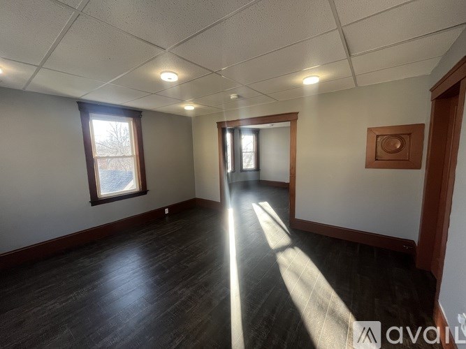 A room with wooden floors and white walls, with sunlight streaming in through a window.