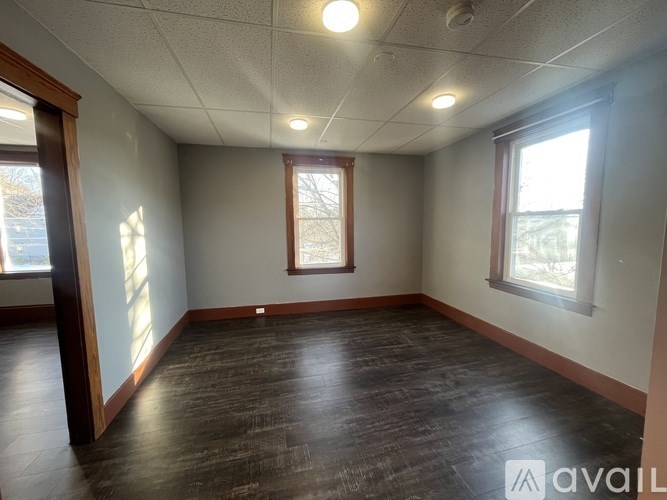 A room with wooden floors and two windows.