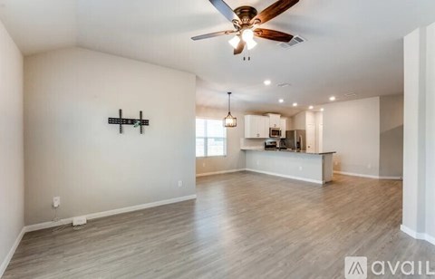 A spacious living room with a ceiling fan and lighting fixtures.
