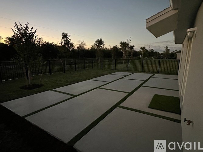 A backyard with a tiled patio and a fence.