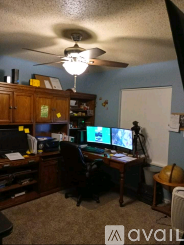 A room with a desk, computer, and a fan.