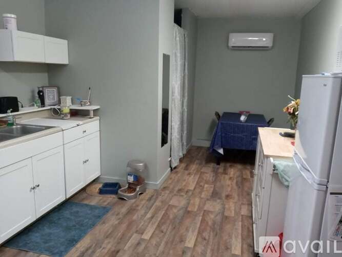 A kitchen with white cabinets and a blue rug on the floor.