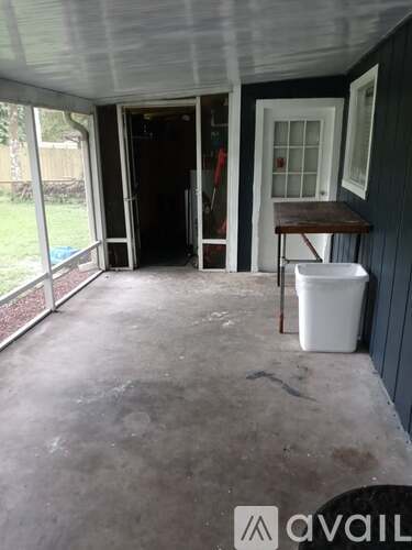 A patio with a white trash can and a table.