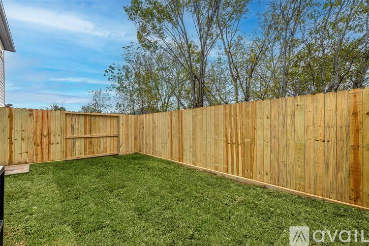 A backyard with a wooden fence and green grass.