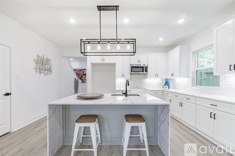 A kitchen with a white island and bar stools.