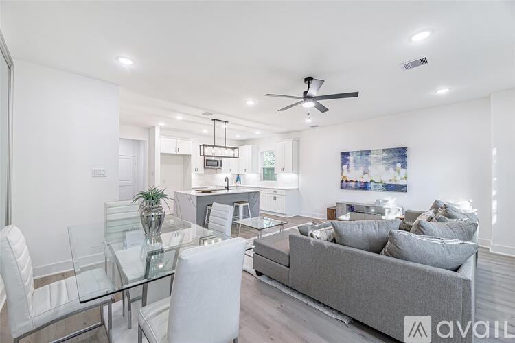 A modern living room with a glass dining table and a grey sofa.