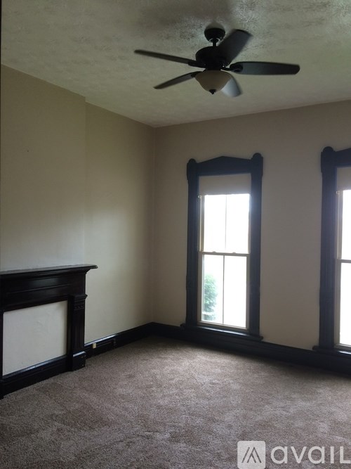 A room with a ceiling fan and two windows.