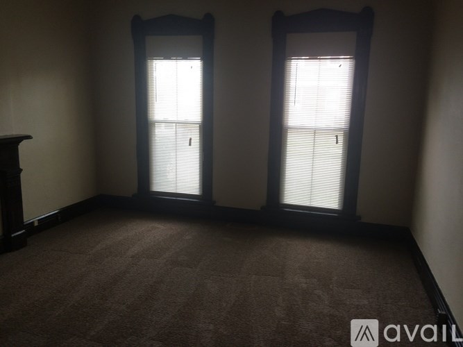 A room with two windows and carpeted flooring.