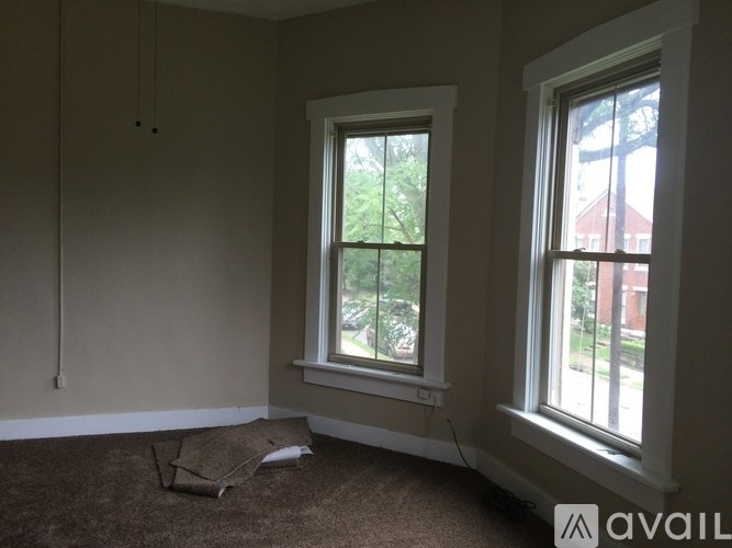 A room with two windows and a carpet on the floor.