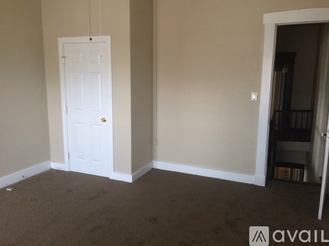 A room with a white door and carpeted floor.