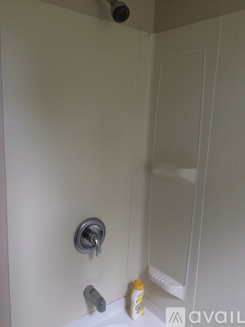 A shower with a yellow bottle on the side.