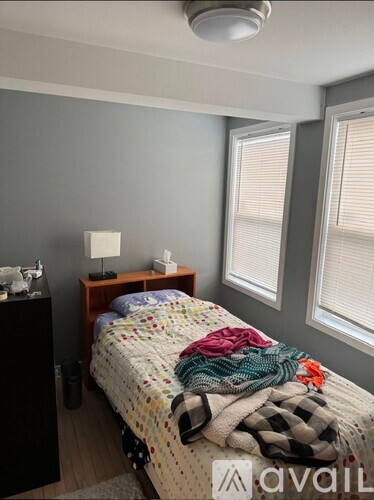 A bedroom with a bed covered in blankets and a nightstand with a lamp.