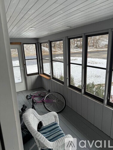 A room with a bicycle and a chair inside.