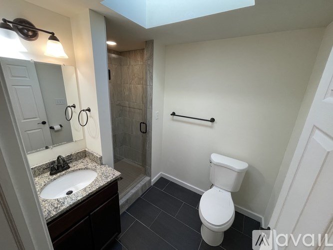 A bathroom with a toilet, sink, and mirror.