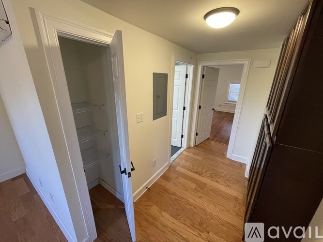 A hallway with a wooden floor and white walls.