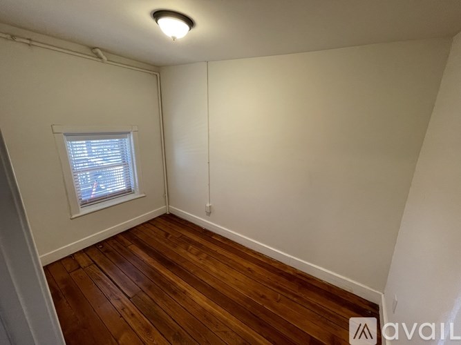 A room with wooden floors and a window with blinds.