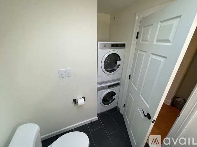 A white toilet sits next to a washing machine in a small room.