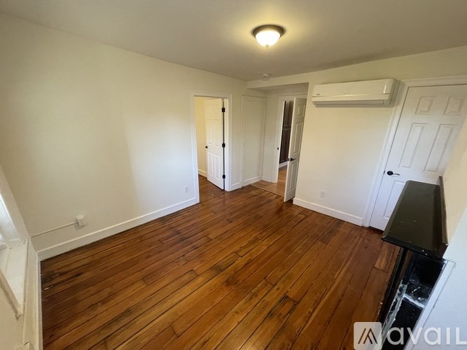 A room with wooden flooring and white walls.