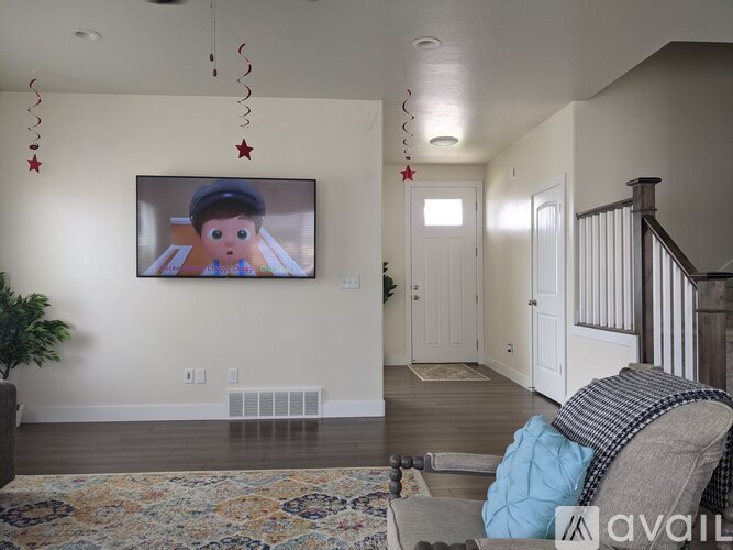 A living room with a television mounted on the wall and a couch with a blue pillow in front of it.