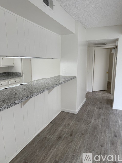 A kitchen with white cabinets and a granite countertop.