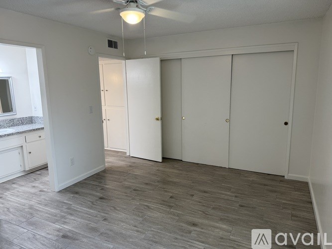 A room with a fan and three closet doors.