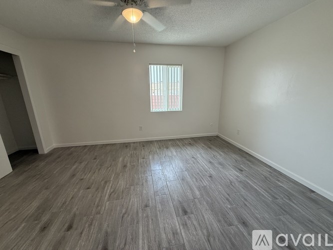 A room with a ceiling fan and a window with blinds.