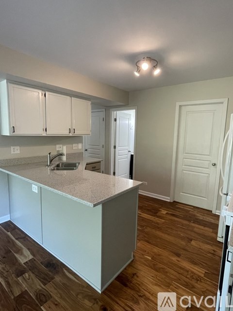 A kitchen with white cabinets and a wooden floor.