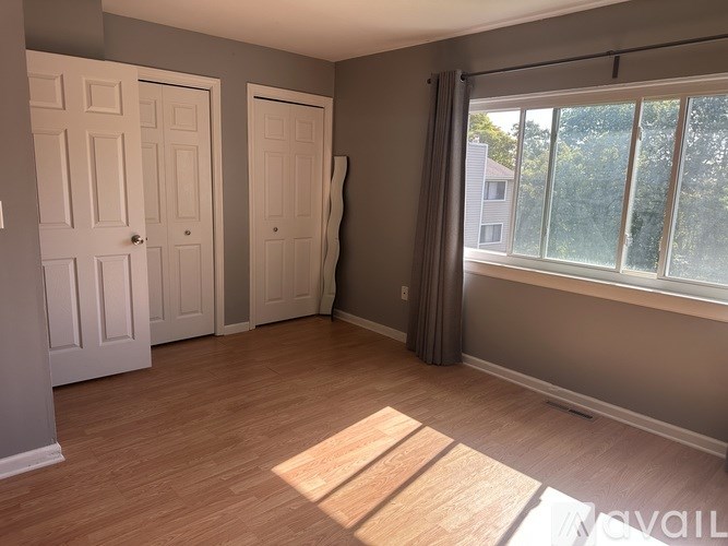 A room with two doors and a window with sunlight coming through.