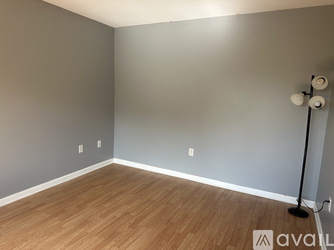 A room with wooden flooring and a light grey wall.