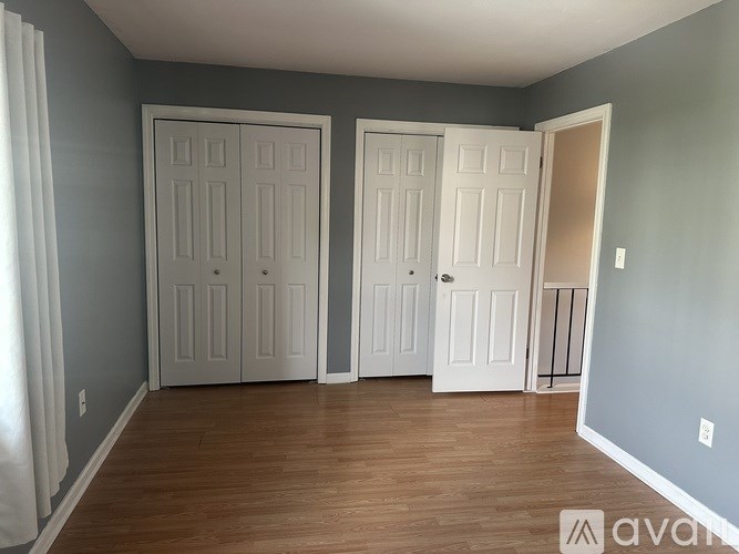 Three white doors in a room with wooden floors and grey walls.
