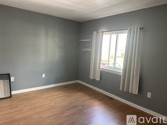 A room with grey walls and a window with white curtains.