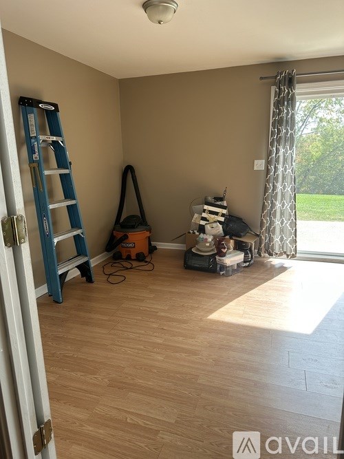 A room with a ladder and vacuum cleaner on the floor.