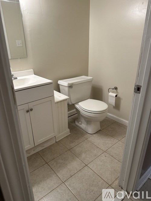 A white toilet sits in a bathroom next to a sink.