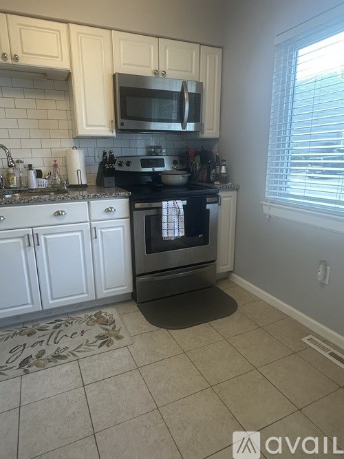 A kitchen with white cabinets and a black stove top oven.