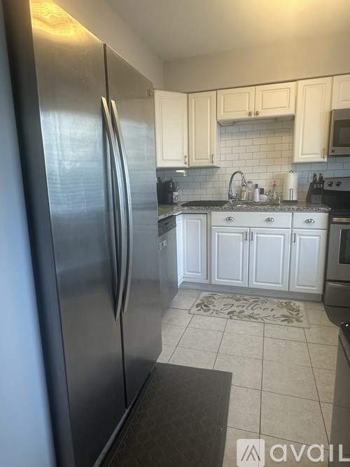 A kitchen with a refrigerator, sink, and cabinets.
