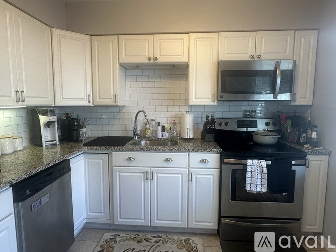 A kitchen with white cabinets and black appliances.