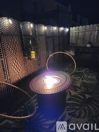 A table with a lit candle on it is in the foreground of an outdoor setting.