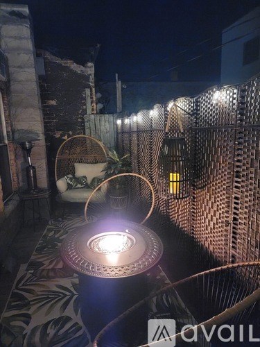A patio area with a table and chairs, a fence, and a lit lantern.