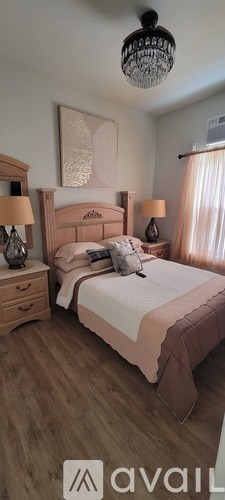 A bedroom with a bed, nightstand, and a chandelier.