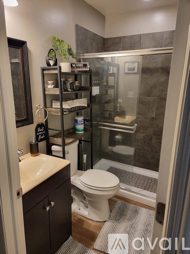 A bathroom with a toilet, sink, and shelves with toiletries.