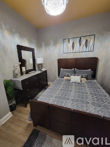 A bedroom with a large bed and a dresser with a mirror.