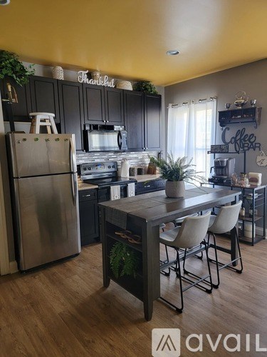 A kitchen with a table and chairs in front of a refrigerator.