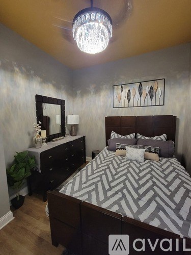 A bedroom with a large bed and a chandelier.