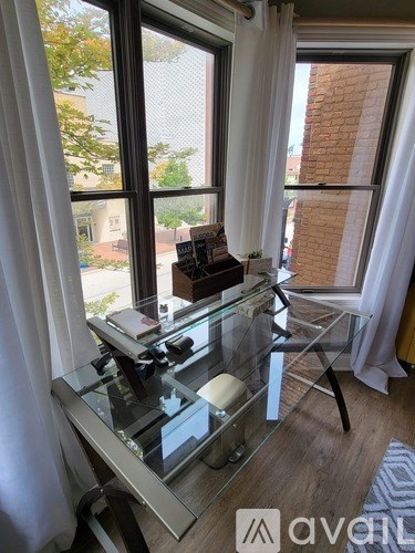 A glass table with a stack of books on it in front of a window.