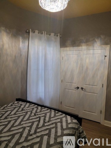 A bedroom with a patterned bedspread and a chandelier.