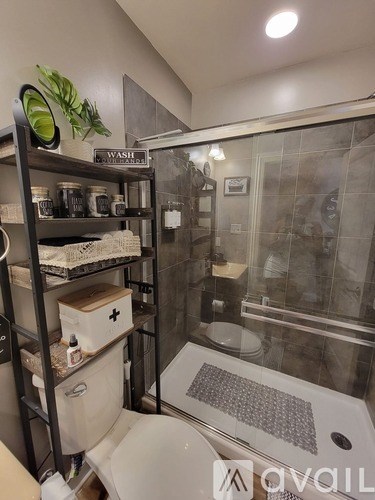 A bathroom with a toilet, sink, and shelves.