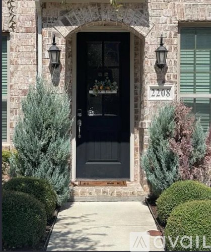A black door with a glass window is flanked by two lights on either side.